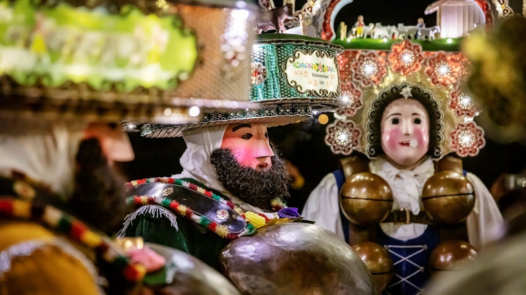 Des hommes costumés et masqués dans un paysage hivernal, à la tombée de la nuit .