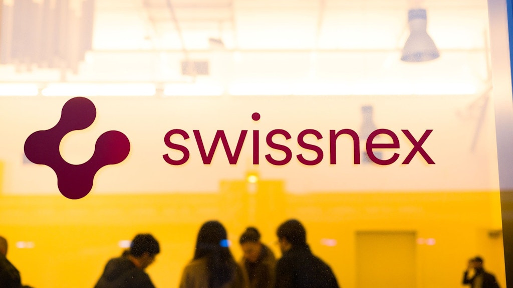 スイスネックスのガラスドアと背景に会議中の人々