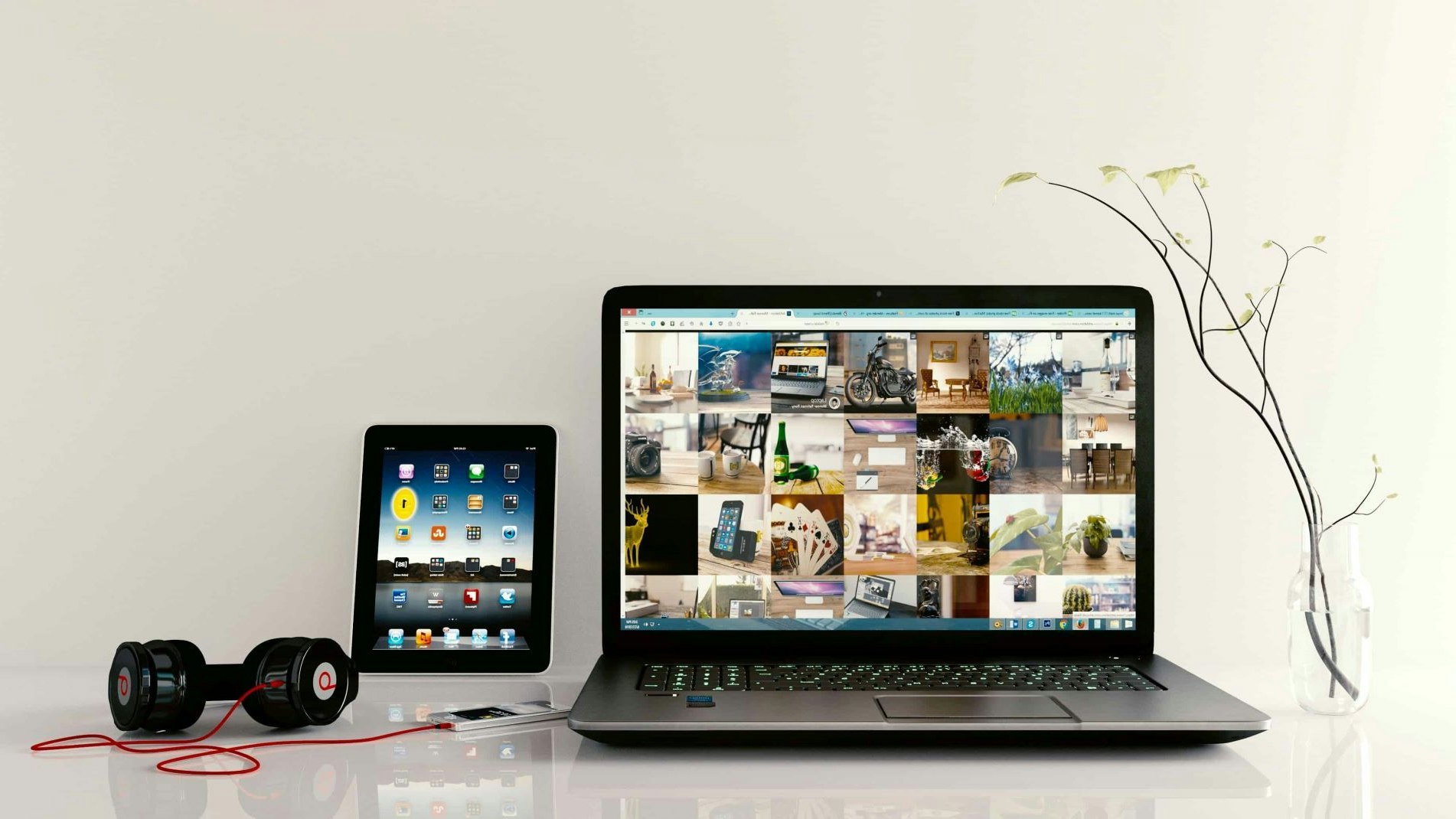 Smartphone avec écouteurs, tablette et ordinateur portable sur une table.