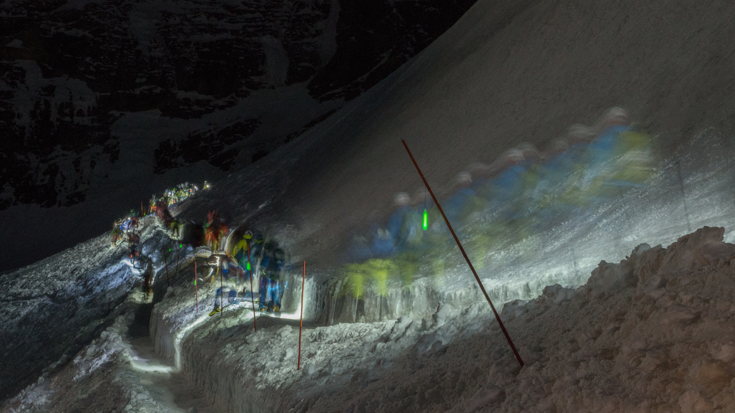 Patrouillen bei Nacht zwischen Schoenbiel und Stockje während der Patrouille des Glaciers, erleuchtet von Stirnlampen auf verschneitem Weg.