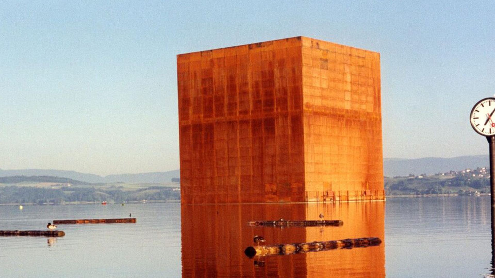 Ein Monolith aus rostigem Metall auf der Oberfläche des Murtensees.
