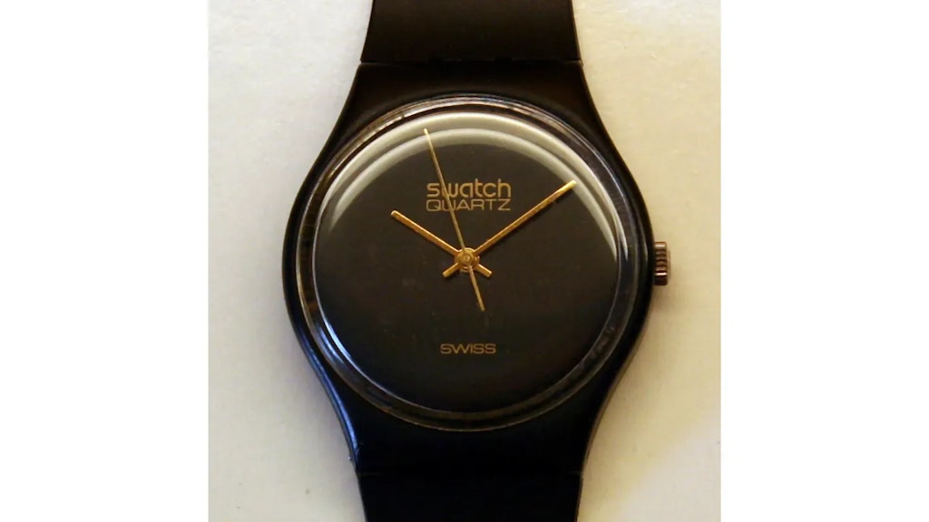 Schwarze Swatch-Uhr mit rundem, schlichtem Zifferblatt, goldenen Zeigern und der Aufschrift «Swatch Quartz» und «Swiss».