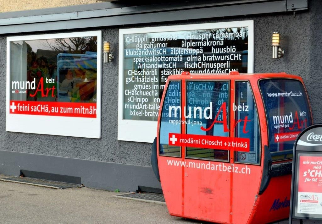 Werbeschilder einer Gastwirtschaft im Deutschschweizer Dialekt.