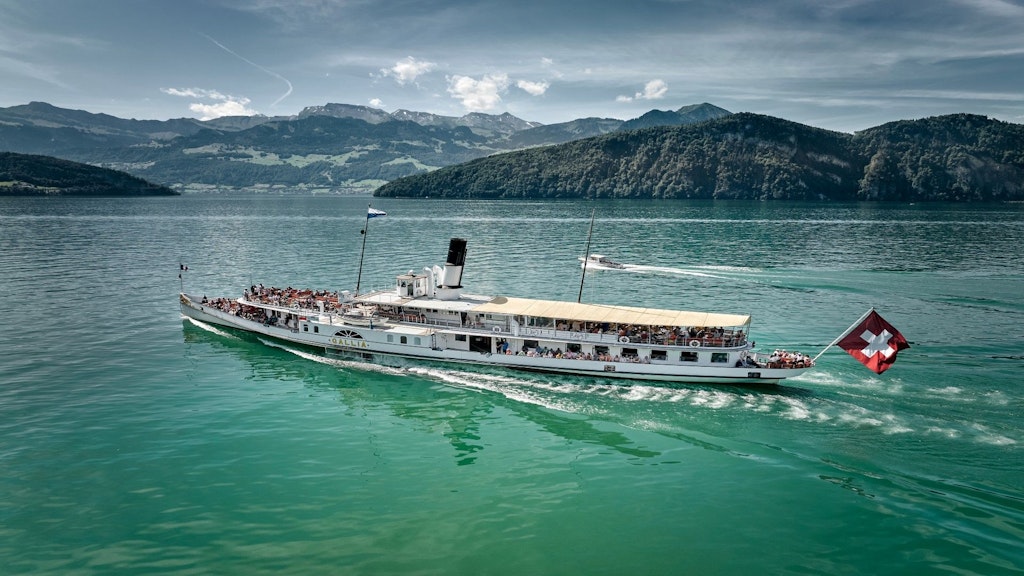 Das Dampfschiff «Gallia» fährt über das türkisblaue Wasser des Vierwaldstättersees. Im Hintergrund sind grüne Hügel zu sehen.