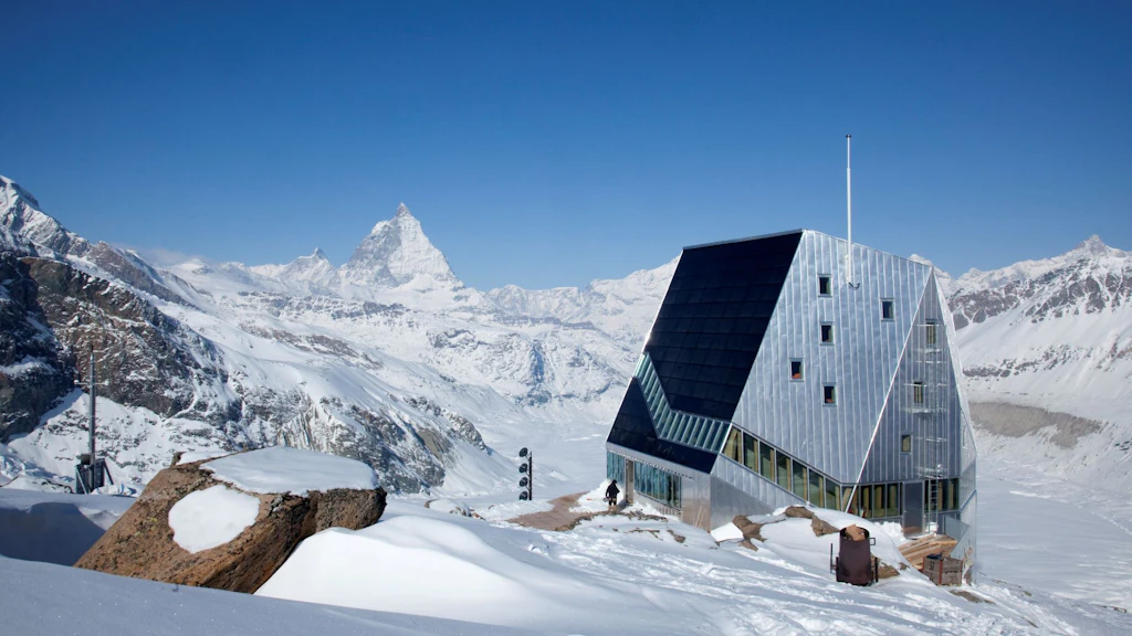 Picture of the Monte Rosa hut in winter with mountains in the background.