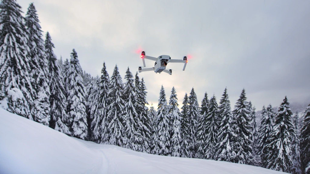 A modern drone flying over a snowy mountain landscape in Switzerland.  