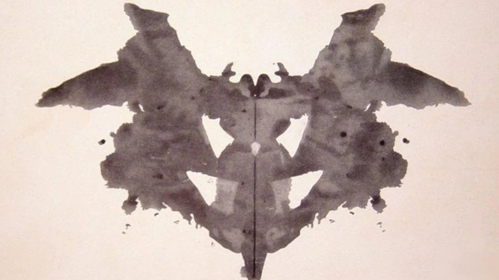 Symmetrical grey inkblot on a white background forming an abstract shape, first card of the Rorschach test.