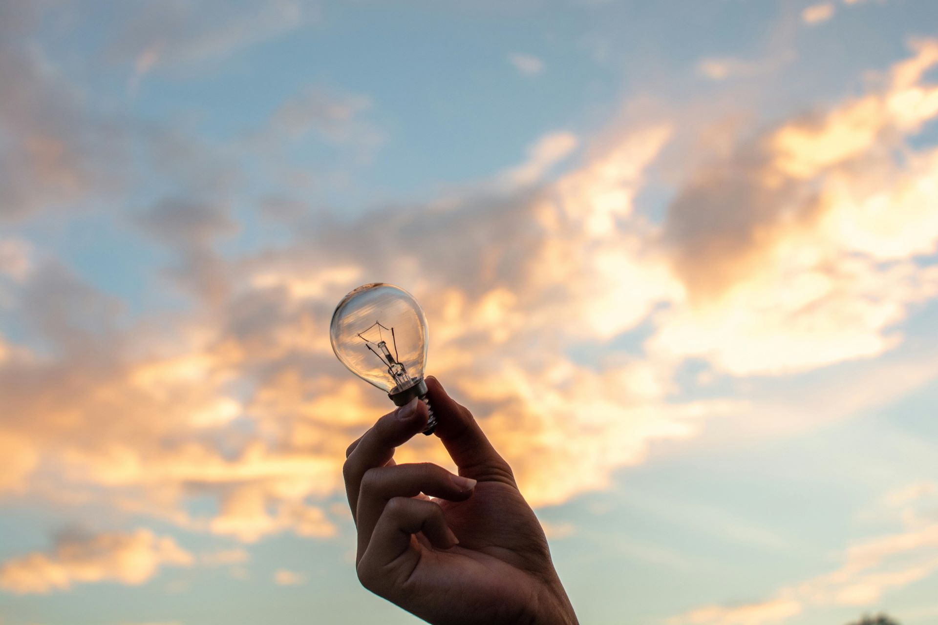 A light bulb in the hand and the sky in the background