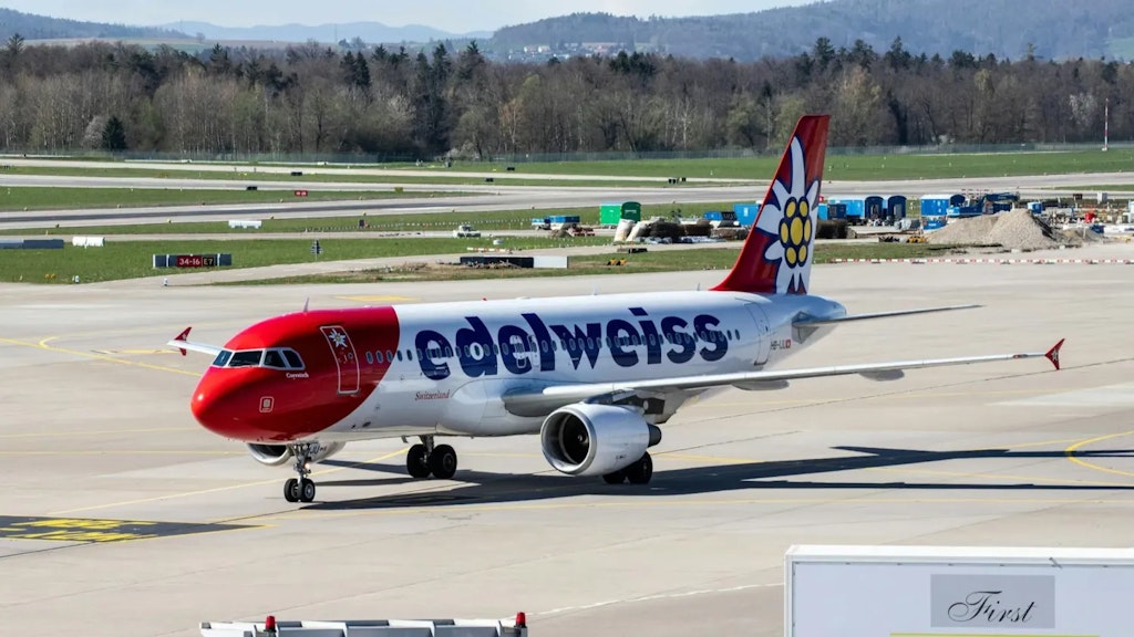 Edelweiss airline plane on an airport tarmac, with red and white livery and an edelweiss flower design on the tail.