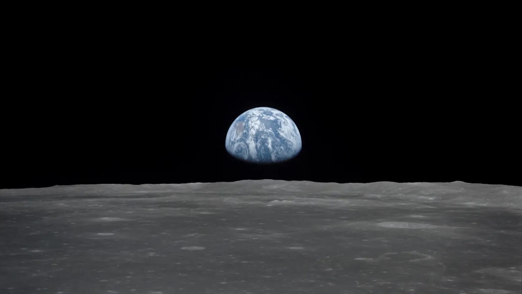 View of the Moon’s grey surface with the blue and white Earth visible on the horizon against a black sky.