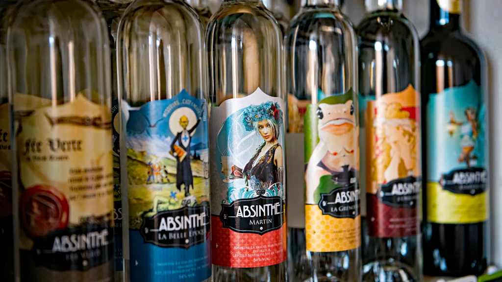 Row of glass bottles filled with absinthe, arranged on a shelf, featuring illustrated labels with varied colours and designs. 
