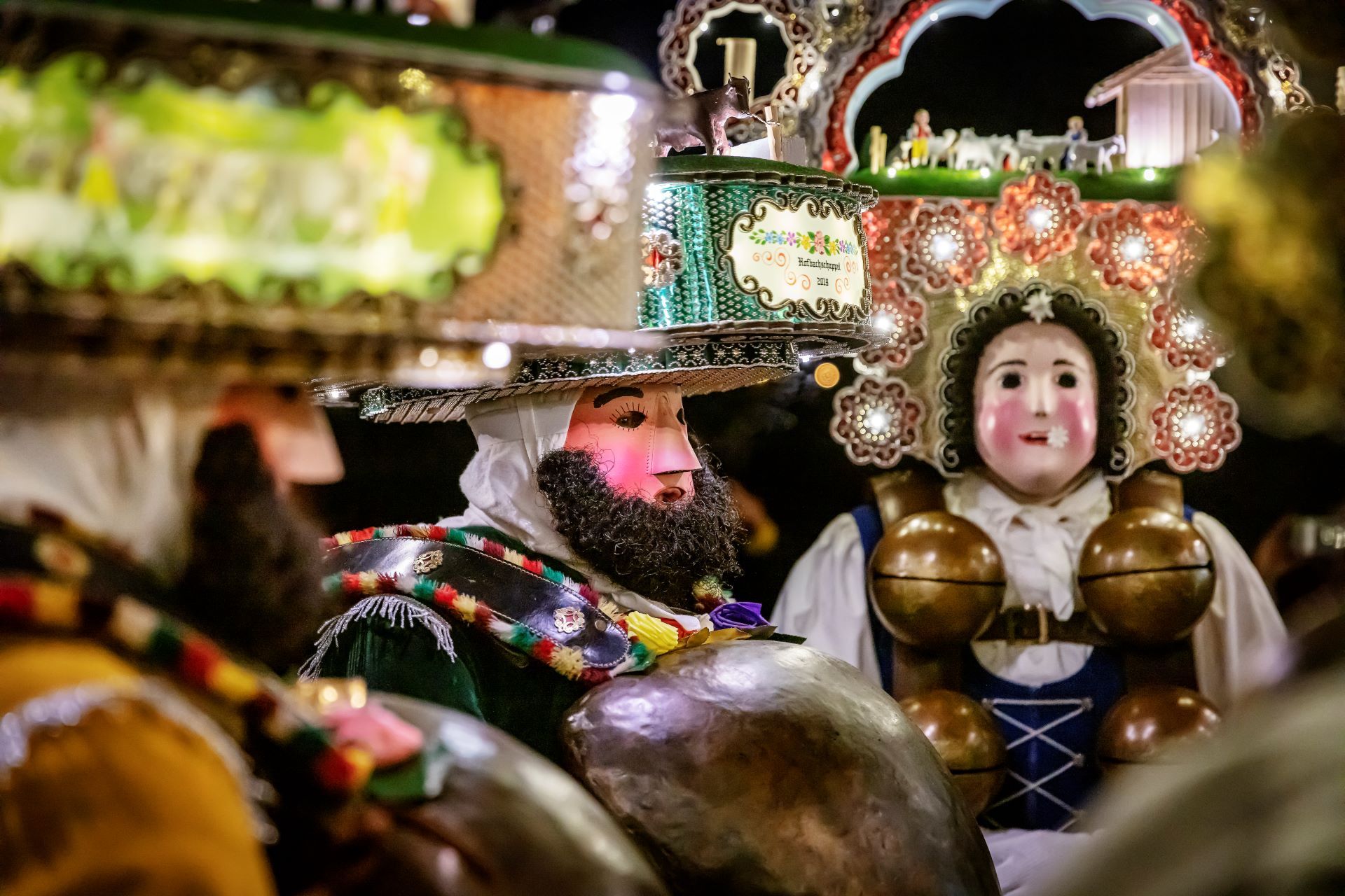 Hombres disfrazados con atuendos y máscaras recorren el vespertino paisaje invernal.