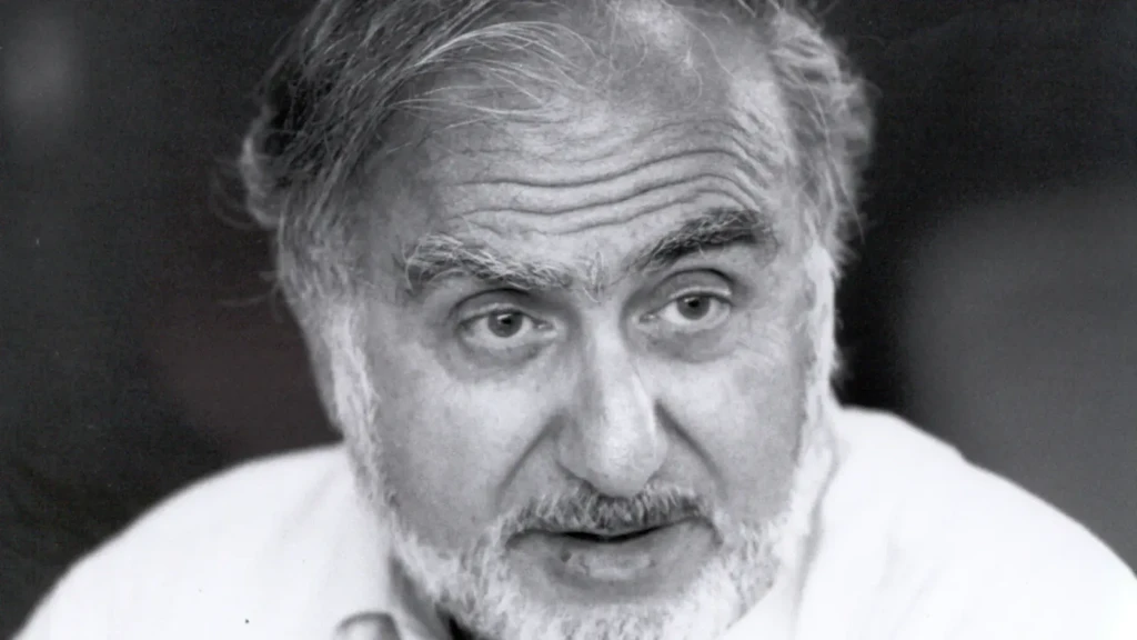 Retrato en blanco y negro de un hombre mayor con barba gris que mira ligeramente hacia la derecha.