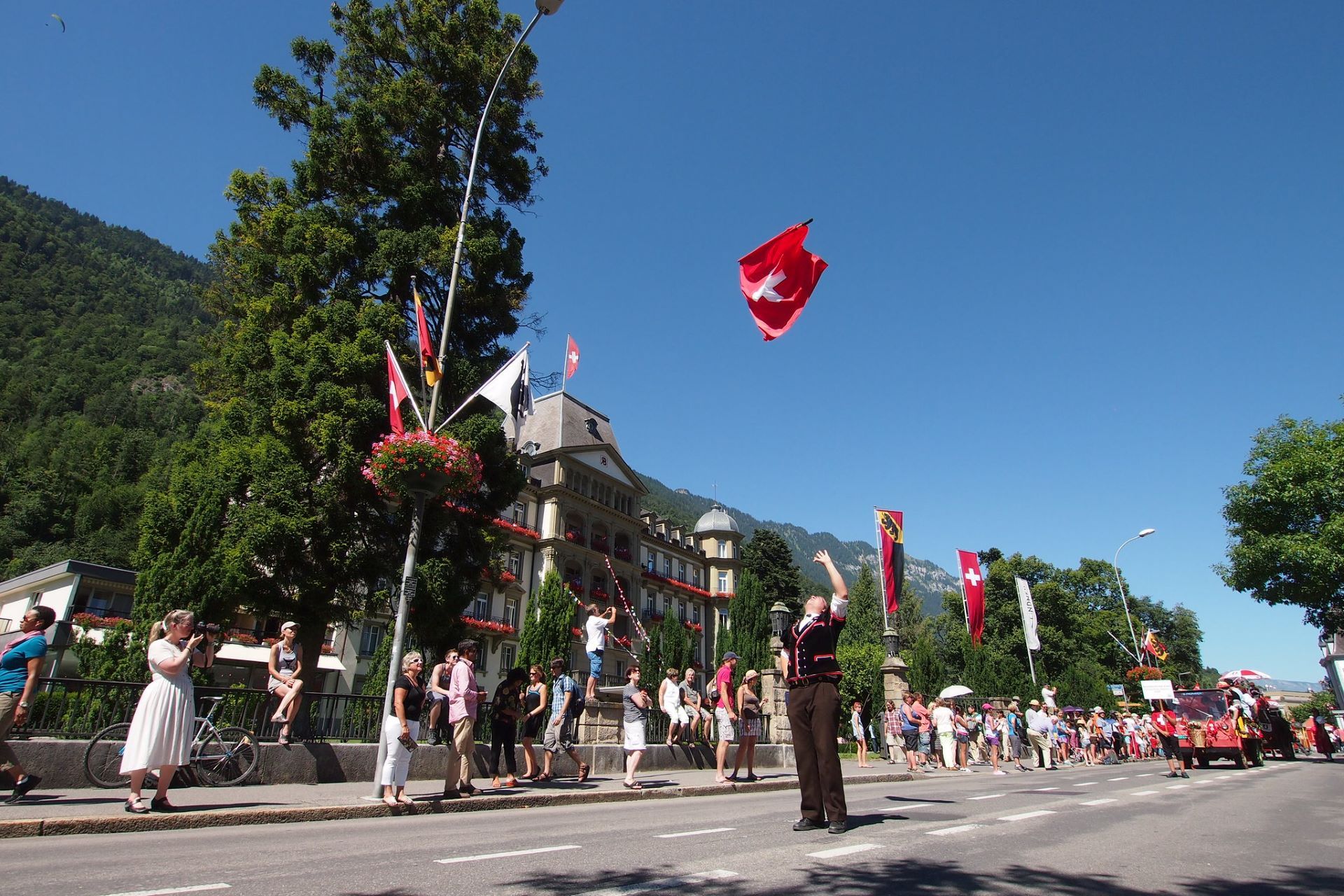 Hombre con traje tradicional ondeando una bandera suiza.