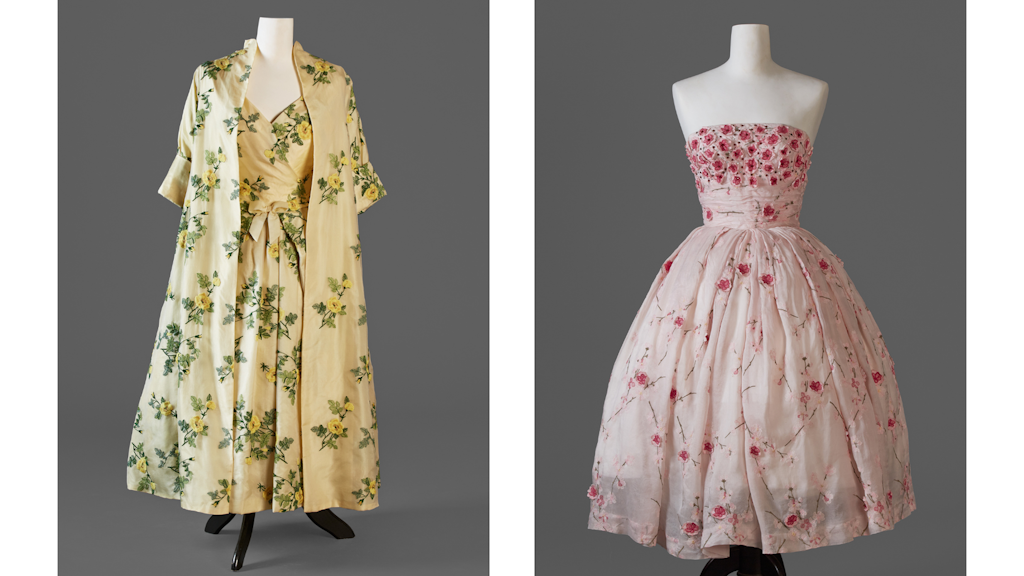 Dos vestidos expuestos en maniquíes: a la izquierda un vestido amarillo con motivos florales verdes, a la derecha un vestido rosa con flores bordadas.