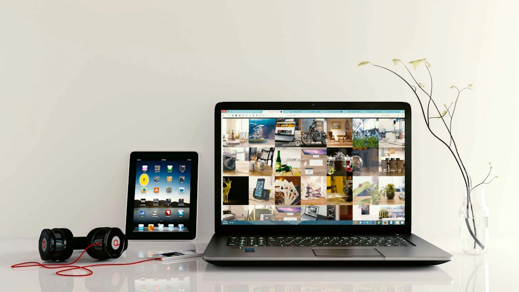 Smartphone con auriculares, tablet y ordenador portátil sobre una mesa. 