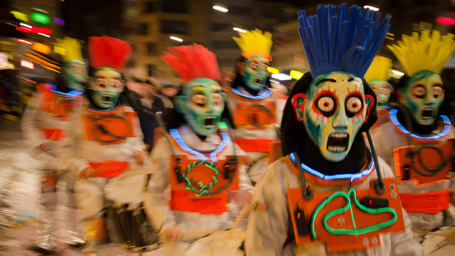 Un groupe de personnes en costumes traditionnels forment une Guggenmusik et traversent une rue.