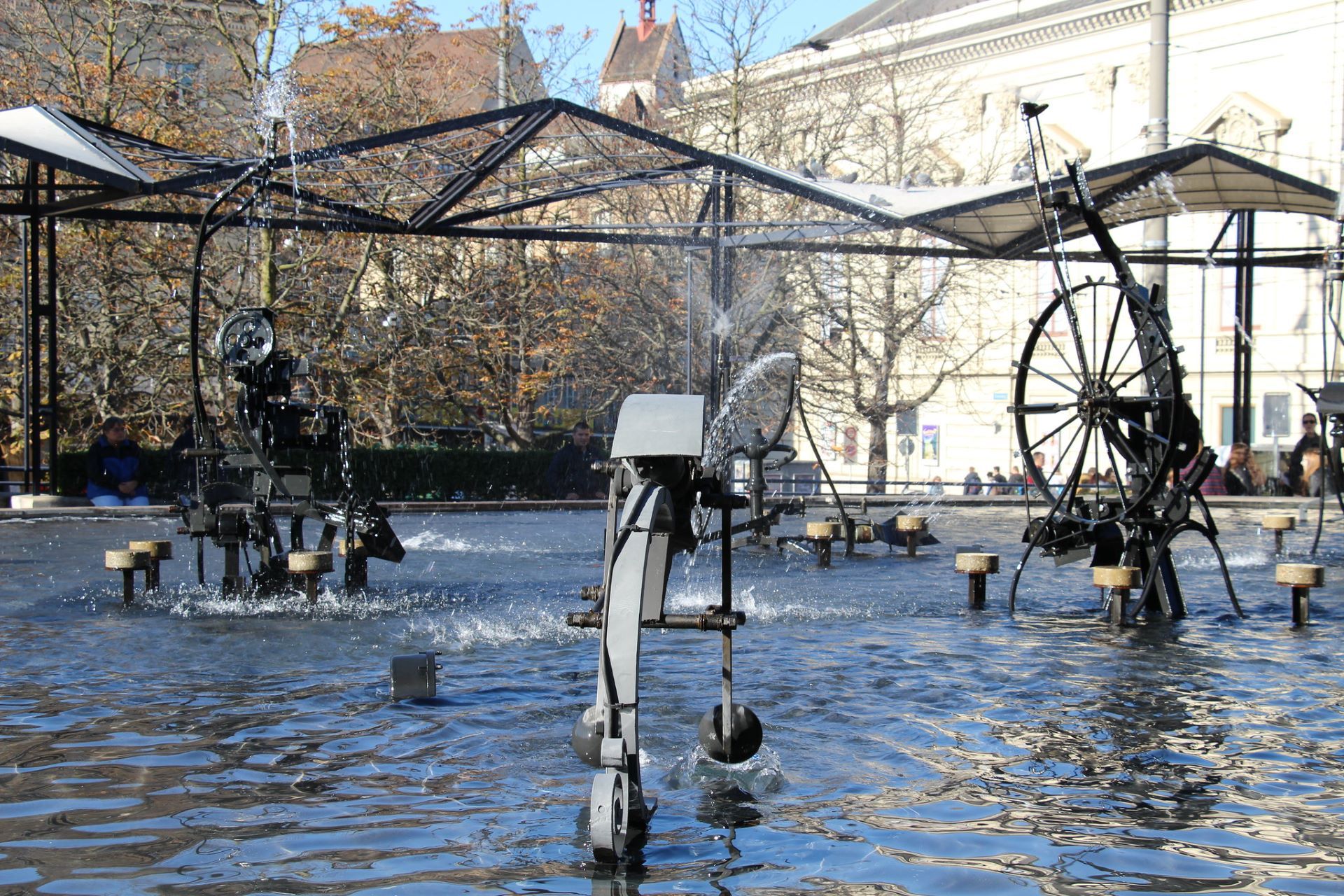 Des sculptures mécaniques, mobiles et aspergeant de l'eau dans l'eau sur la place du Théâtre à Bâle.