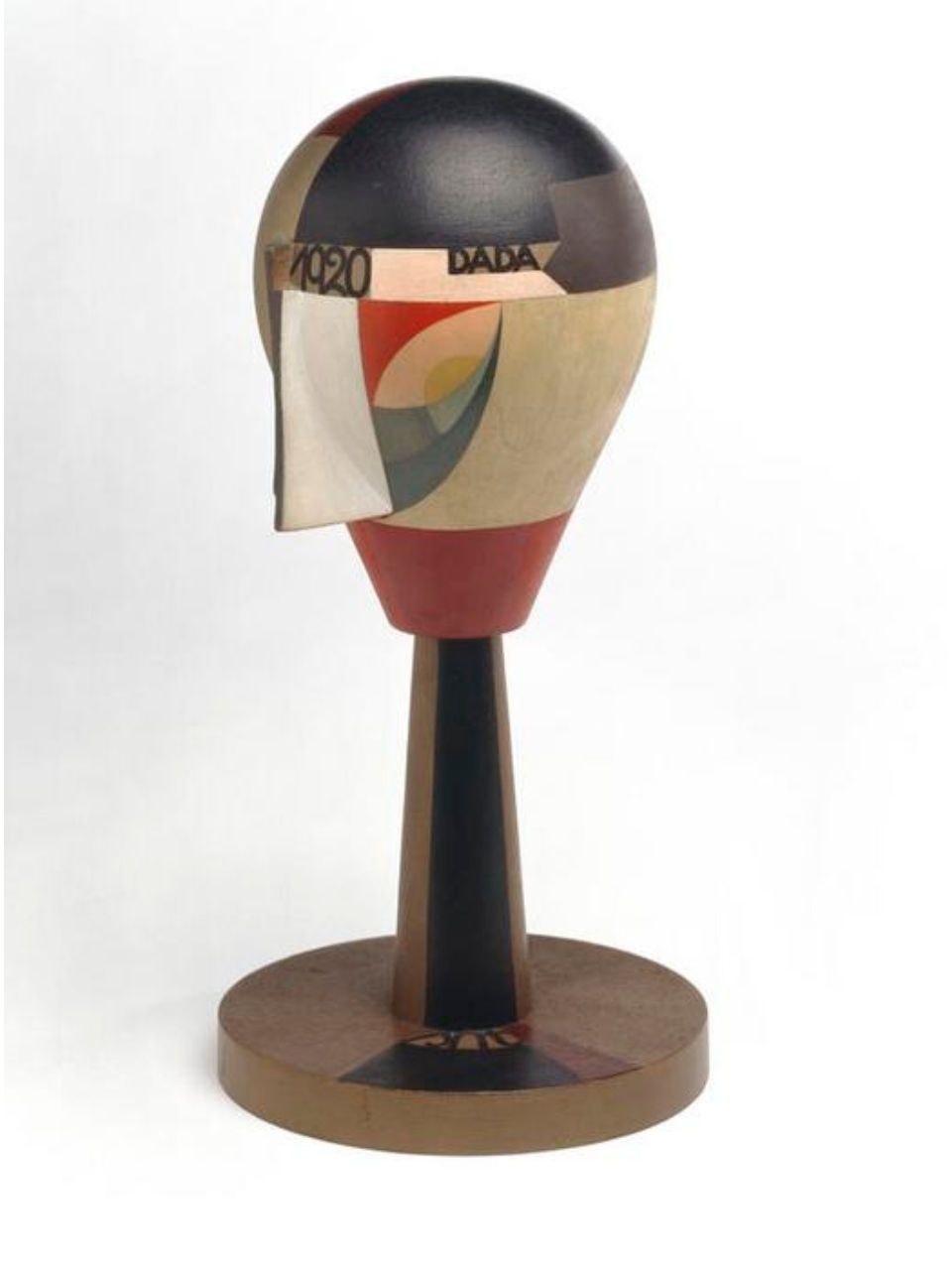 Photographie de la sculpture «Tête de Dada» (1920) de Sophie Taeuber-Arp: forme hélicoïdale stylisée en bois peint en aplats géométriques rouge, noir, beige et gris. 