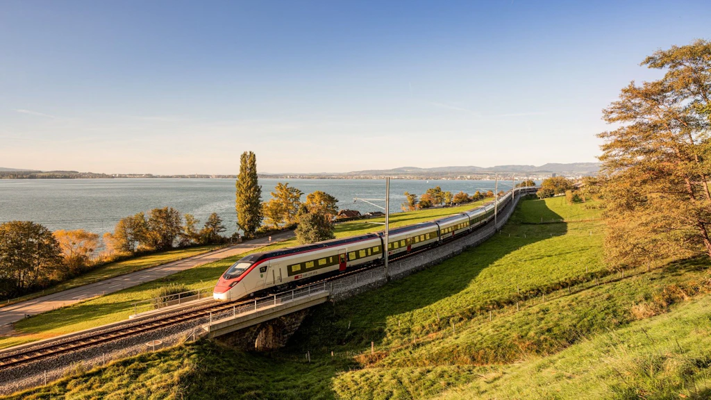 Un train des CFF longe le lac de Zoug dans une lumière dorée.  