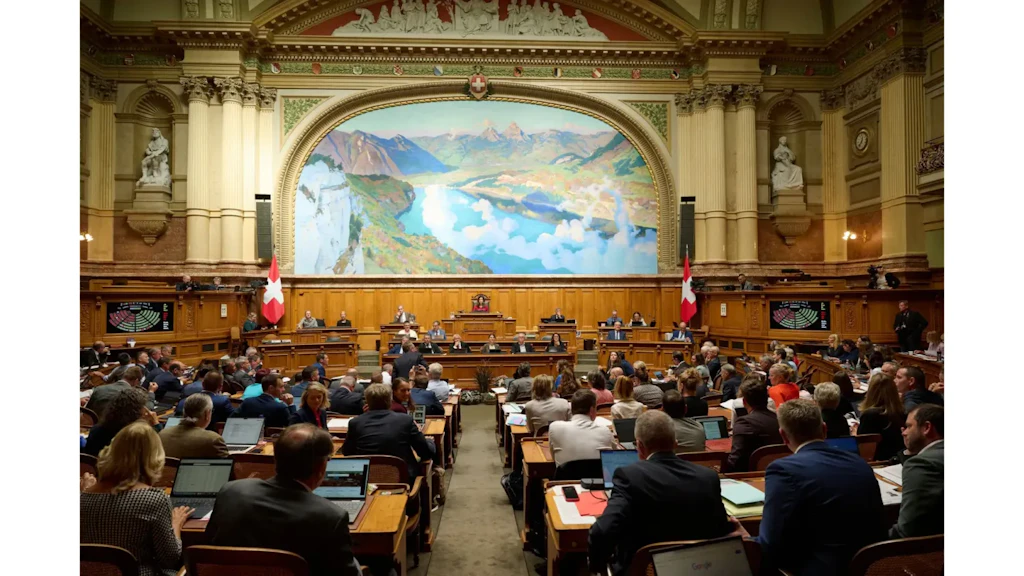 Vista della sala del Consiglio nazionale con deputati ai banchi, bandiere svizzere e grande affresco alpino sulla parete.