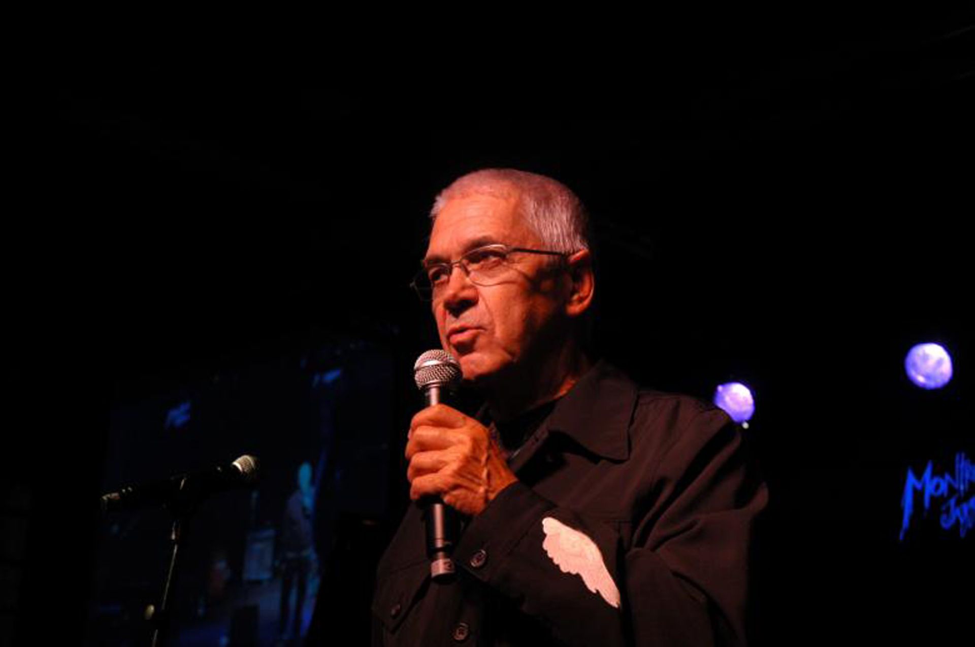Claude Nobs, il cofondatore del Montreux Jazz Festival, tiene un microfono e parla sul palco.