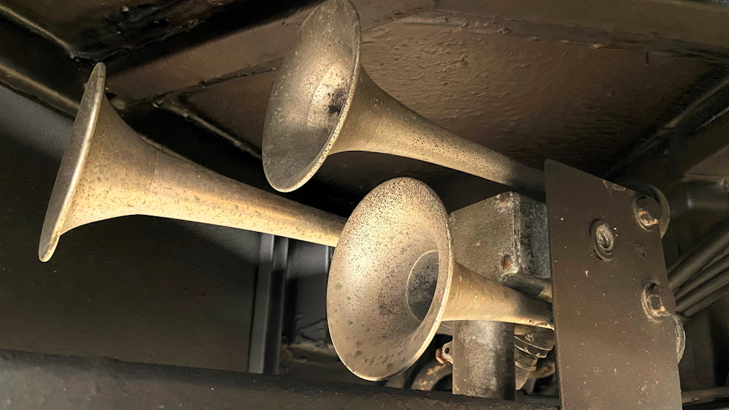 Tre trombe metalliche usurate montate sotto un veicolo, rivolte in avanti, fissate a un supporto metallico con cavi in vista.