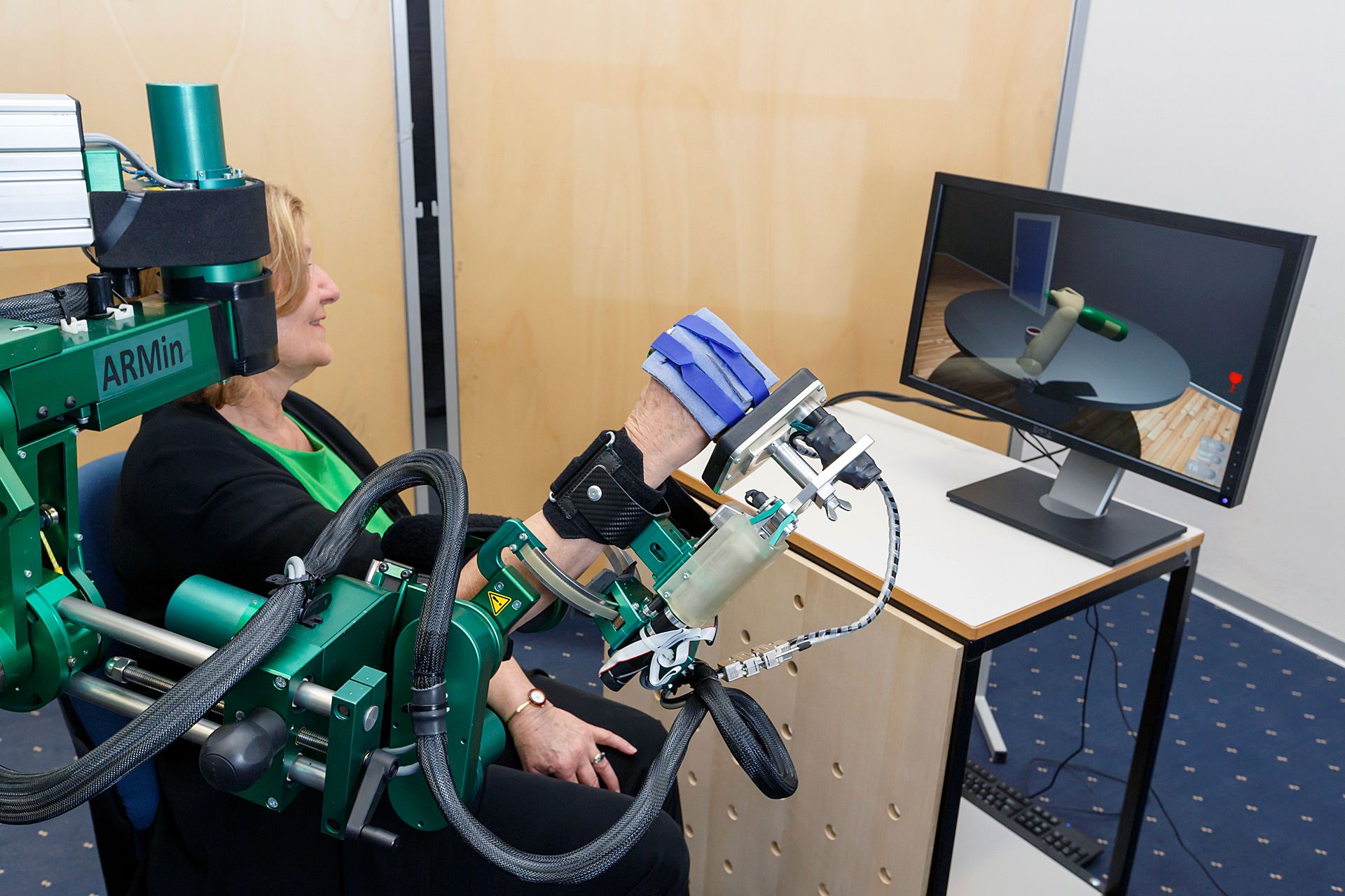 Sessione di fisioterapia con un dispositivo robotico davanti a uno schermo.