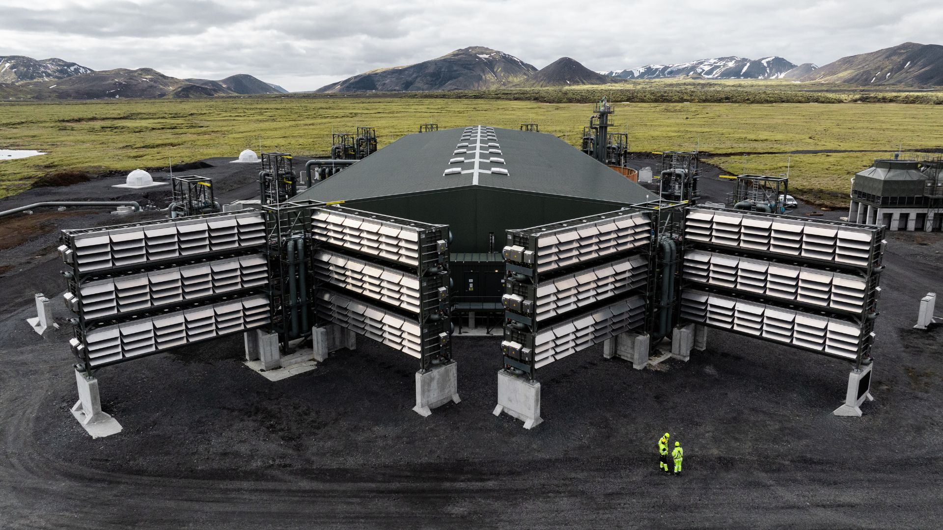 曇り空の下、火山地帯に設置されたコンテナ型モジュール、配管、ファンを備えたアイスランドの大規模産業施設。