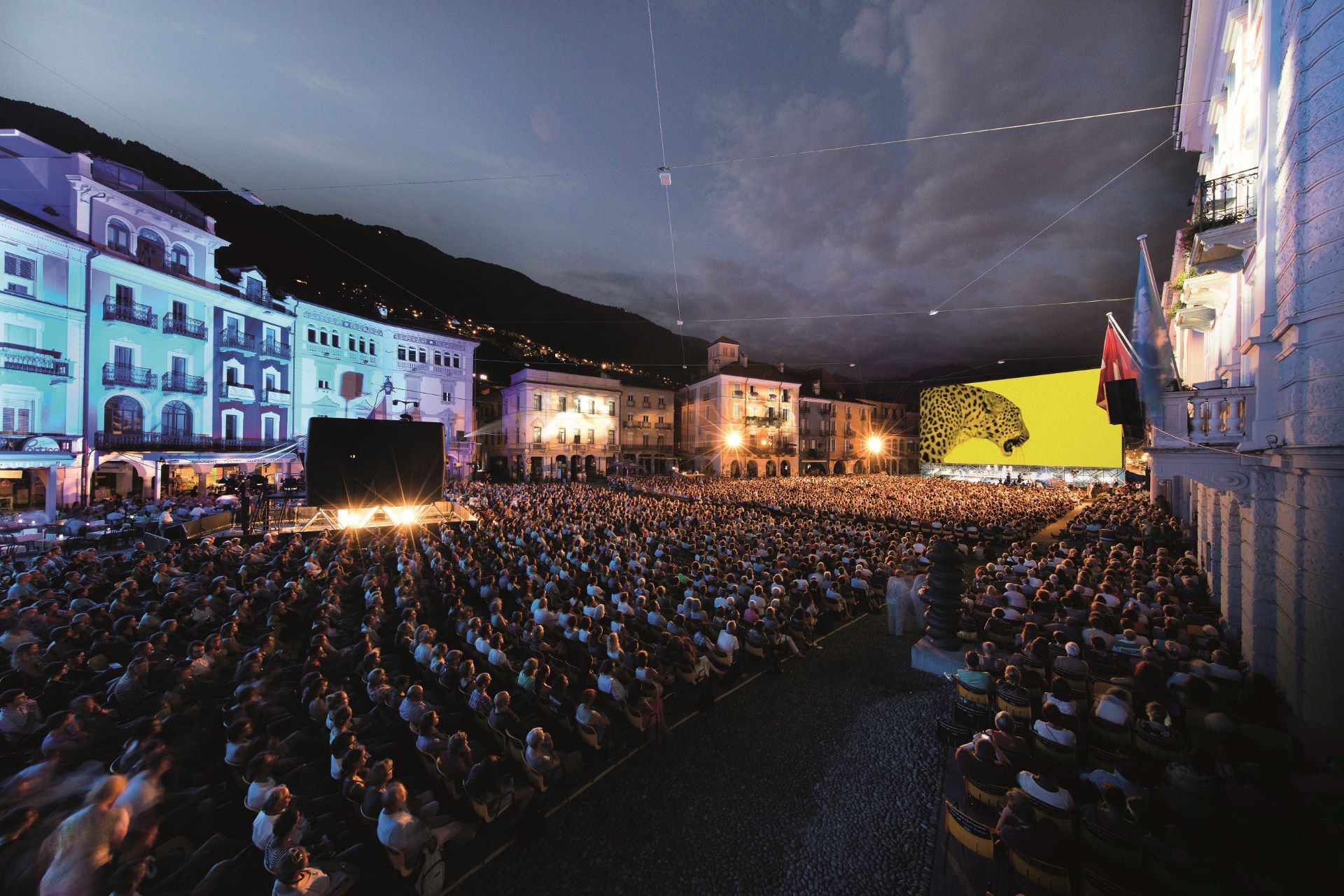 Cinema ao ar livre à noite na Piazza Grande, em Locarno, com milhares de espectadores.