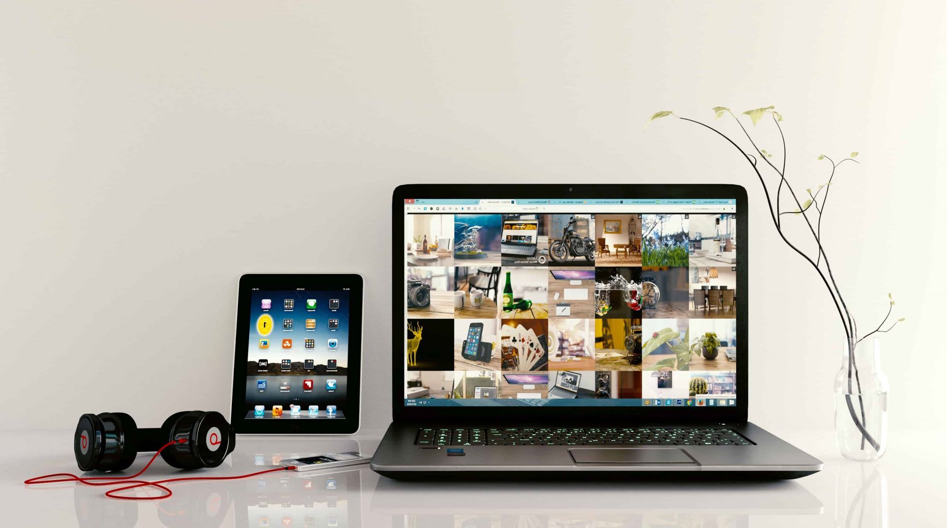 Smartphone com fones de ouvido, tablet e notebook em uma mesa.